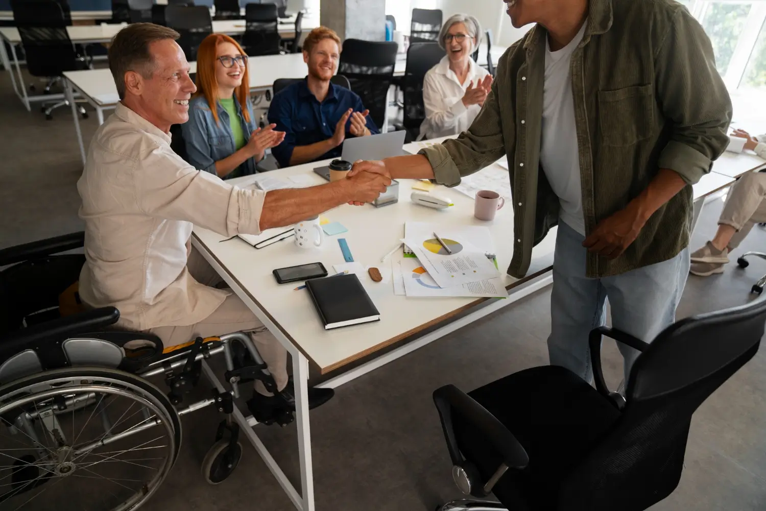 Wheelchair user shaking hands with a colleague during an inclusive workplace meeting