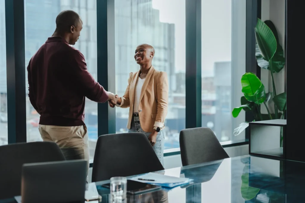Two professionals shaking hands in a modern office meeting room