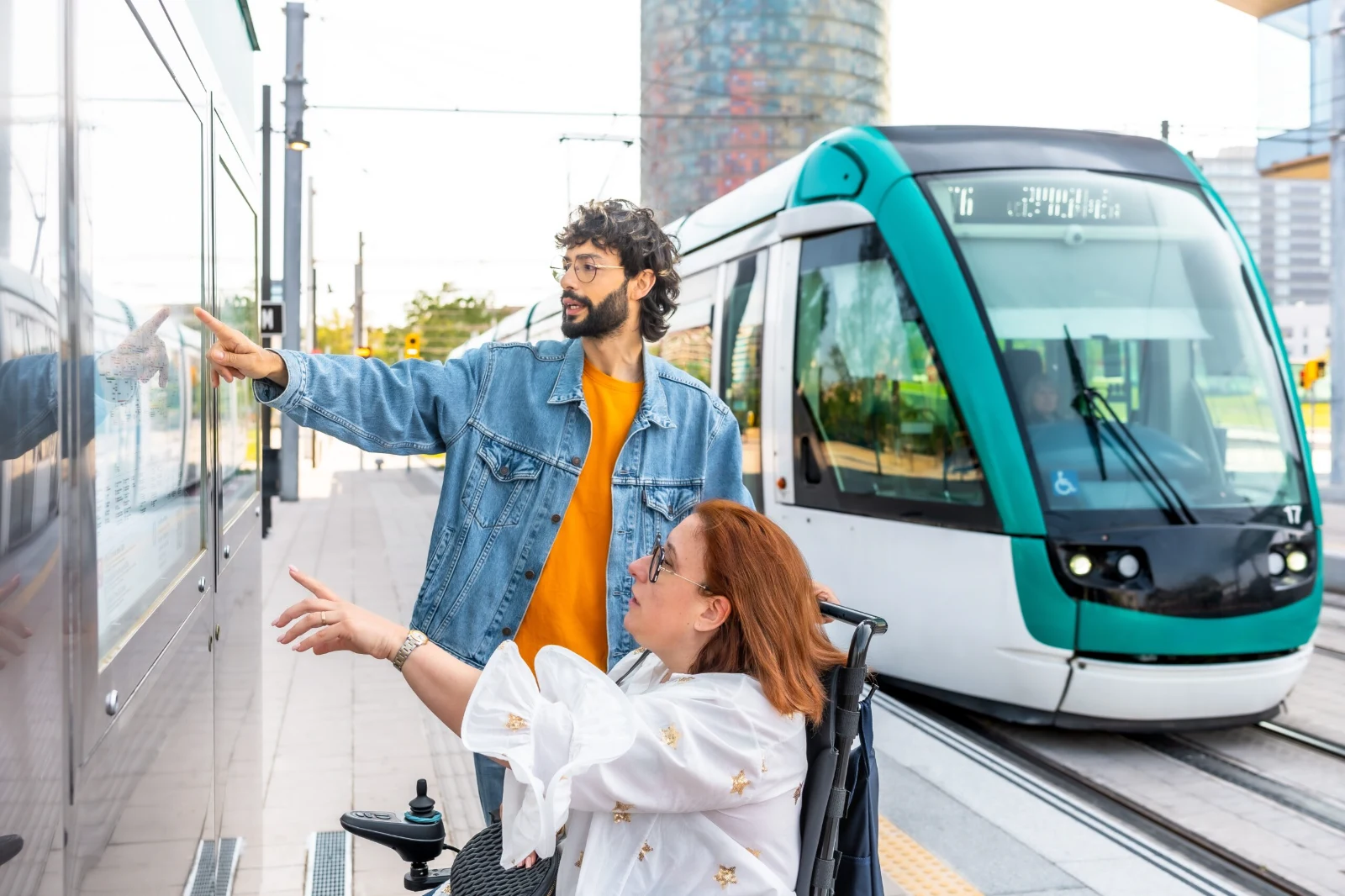 Wheelchair user and companion checking a transit map at an accessible tram station