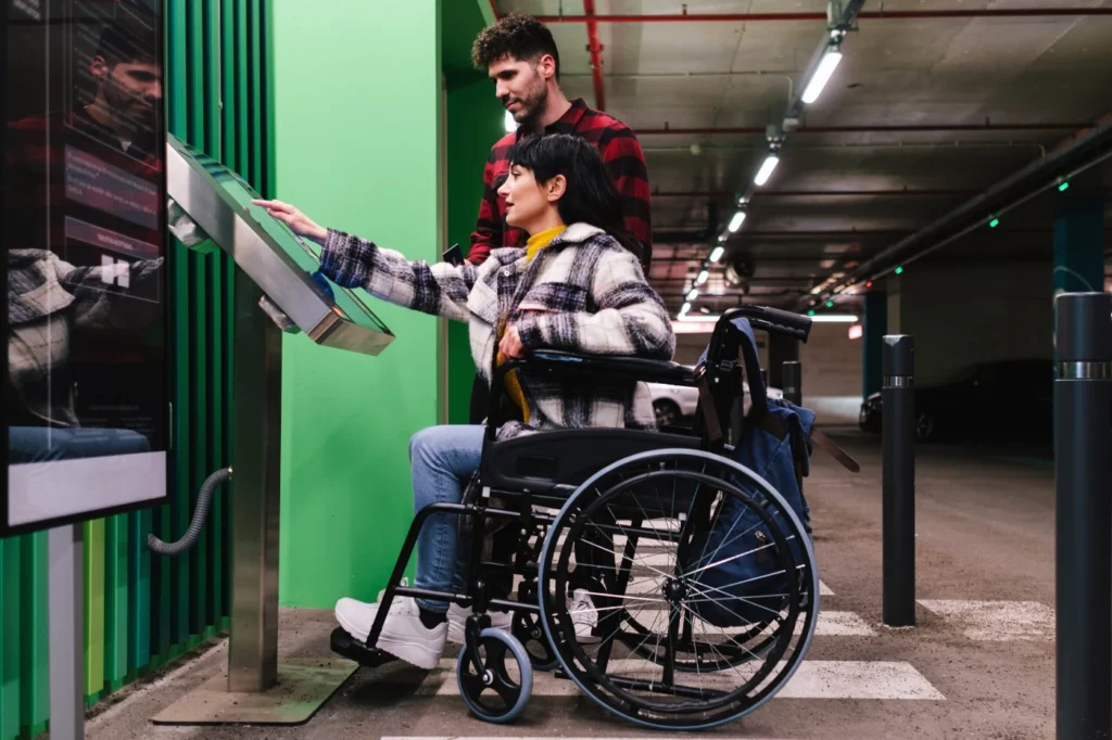 Wheelchair user using an accessible payment kiosk in a parking garage
